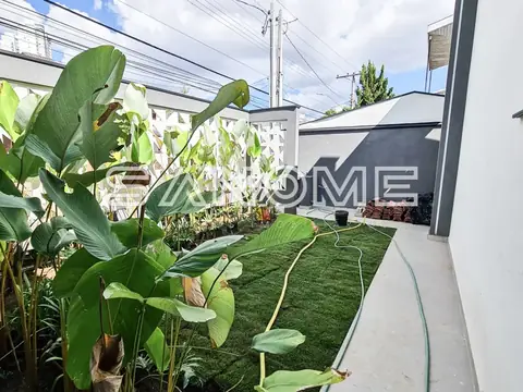 Área externa com grama sintética e plantas ornamentais