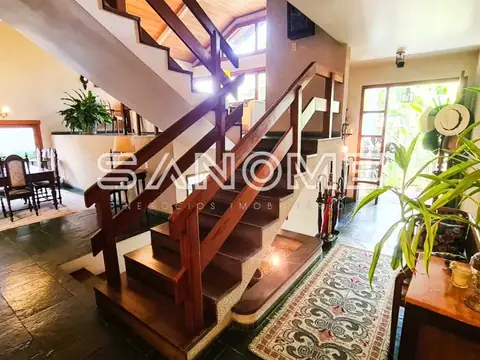 Sala de entrada com escada de madeira e plantas