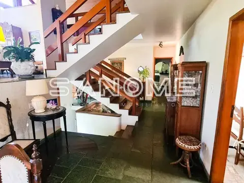 Hall de entrada com escada de madeira e plantas