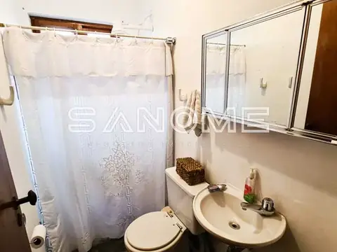 Banheiro com vaso sanitário, pia e chuveiro com cortina