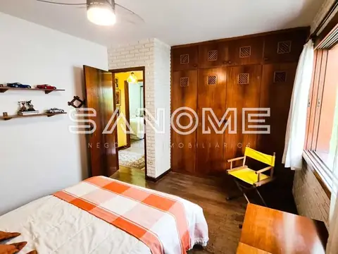 Quarto com cama, guarda-roupa em madeira e poltrona amarela