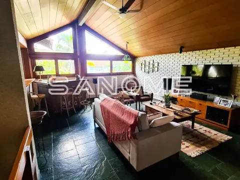 Sala de estar com sofá, TV e janelas amplas