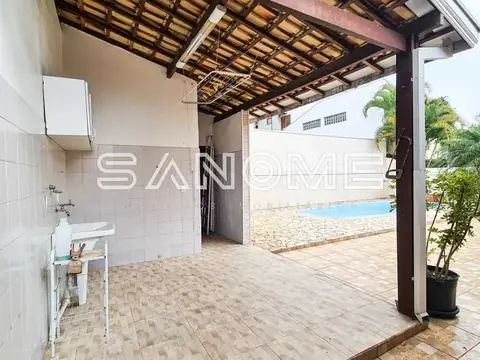 Área externa com pia, pergolado e piscina ao fundo