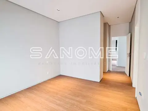Sala vazia com piso de madeira e parede divisória branca