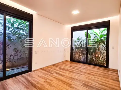 Sala com piso de madeira e portas de vidro para área externa