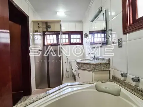 Banheiro com banheira, pia e box de vidro