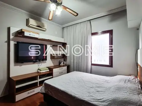 Quarto com cama de casal e TV na parede