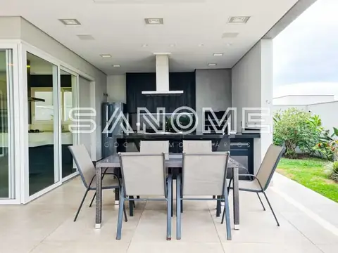 Área externa com mesa de refeições e cozinha integrada