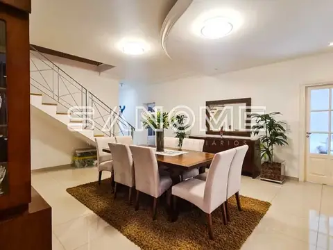 Sala de jantar com mesa de madeira e cadeiras estofadas