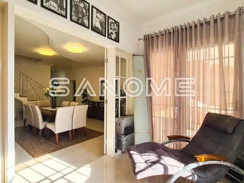 Sala de estar com poltrona e acesso à sala de jantar