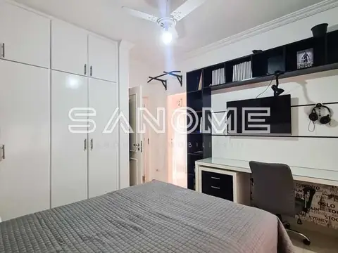 Quarto com cama, guarda-roupa branco e painel preto