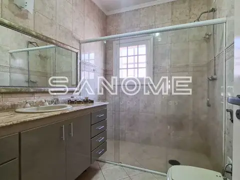 Banheiro com bancada, espelho e box de vidro