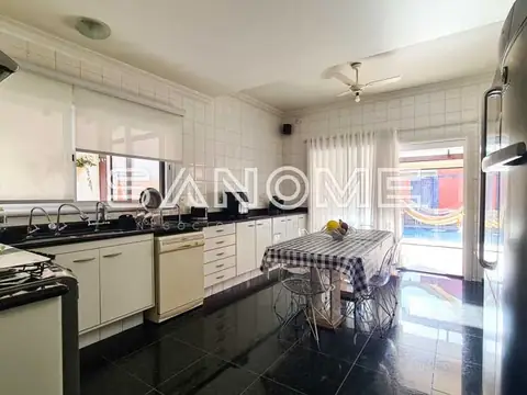 Cozinha com piso preto e bancada com mesa de refeições