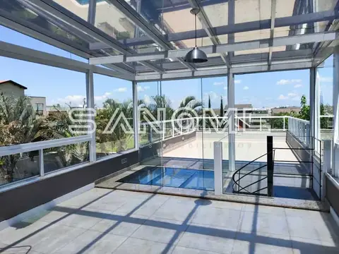 Área de convivência com cobertura de vidro e vista para jardim