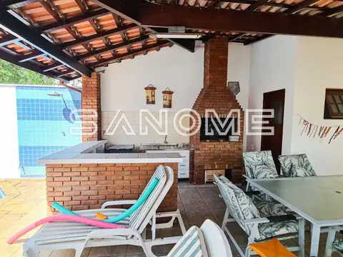 Área externa com churrasqueira e piscina ao fundo