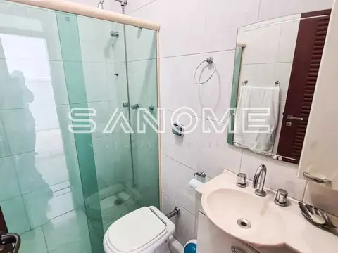 Banheiro com chuveiro box, pia dupla e espelho