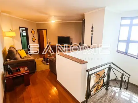 Sala de estar com sofá, TV e escada de acesso