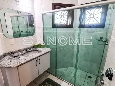 Banheiro com bancada em granito e box com azulejos verdes