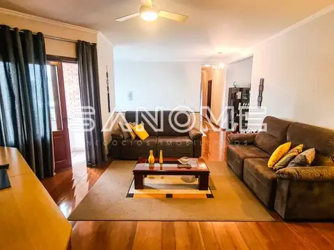 Sala de estar com sofá marrom e piso de madeira