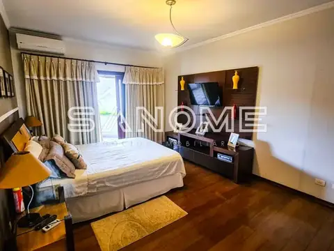 Quarto com cama de casal e painel de TV