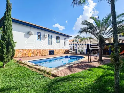 Área externa de casa com piscina e palmeiras