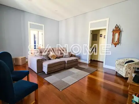Sala com sofá, poltronas e piso de madeira