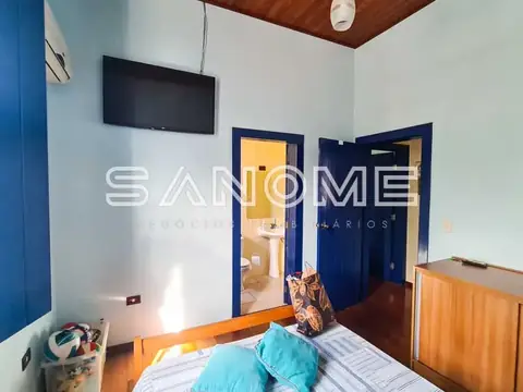 Quarto com cama, portas azuis e TV na parede