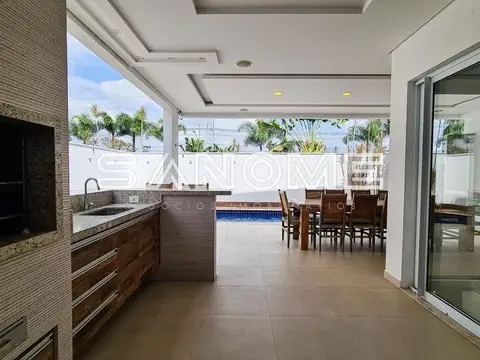 Área de lazer com cozinha e piscina ao fundo