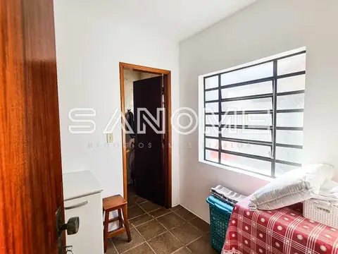 Quarto com cama, janela com grades e porta de entrada