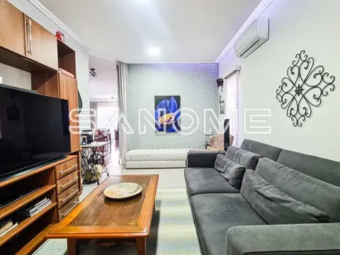 Sala de estar com sofá cinza e painel de TV em madeira
