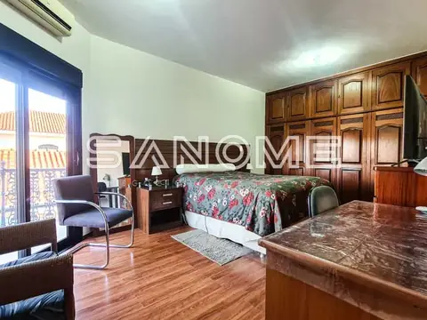 Quarto amplo com cama de casal e móveis em madeira