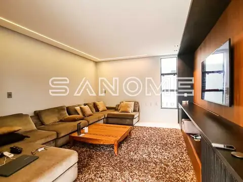 Sala de estar com sofá em L e painel de TV