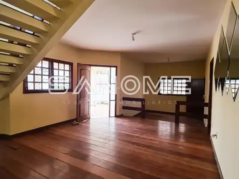 Sala com piso de madeira e escada ao fundo