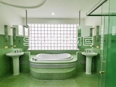 Banheiro com banheira central e pias duplas em verde