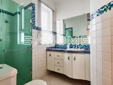 Banheiro com espelho, pia e box com vidro verde