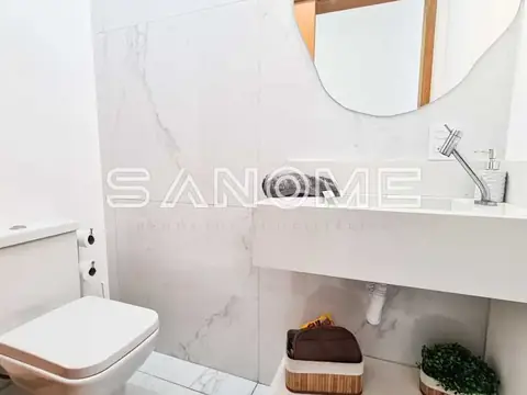Banheiro com pia, espelho e box com revestimento em mármore