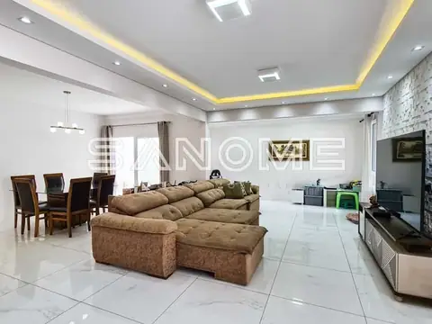 Sala ampla com sofá marrom e painel de TV