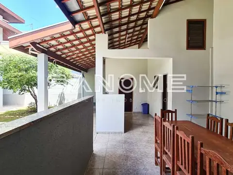 Área externa coberta com mesa de madeira e churrasqueira