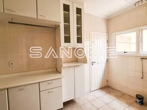 Cozinha com bancada, armários e azulejos bege