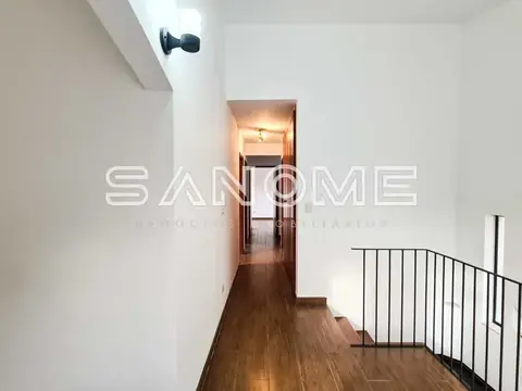 Corredor interno com piso de madeira e guarda-corpo metálico