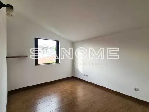 Quarto vazio com piso de madeira e janela