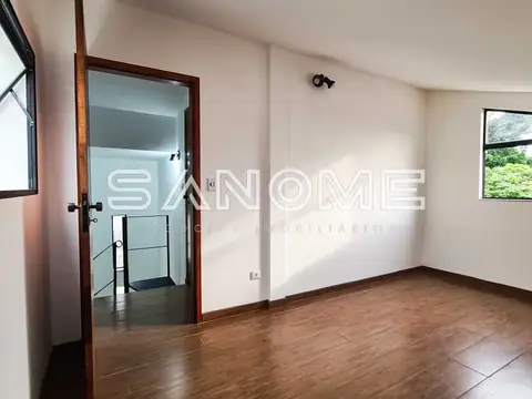 Sala com piso em madeira e porta de vidro para escada
