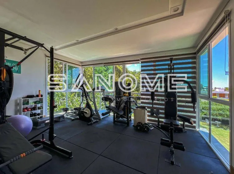 Sala de ginástica com equipamentos e grandes janelas