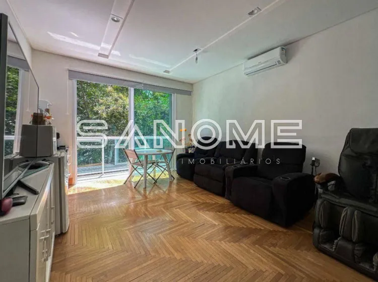 Sala de estar com sofá, piso em madeira e varanda