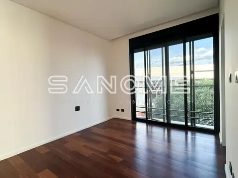 Quarto com piso de madeira e sacada com vista externa