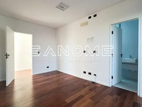 Quarto com piso de madeira e banheiro integrado