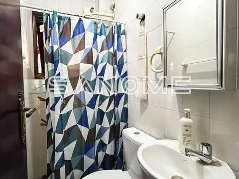 Banheiro com chuveiro, pia e cortina azul geométrica