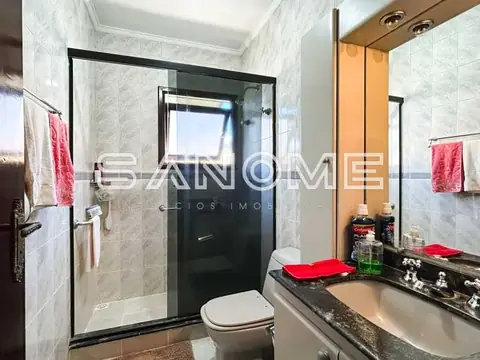 Banheiro com bancada, espelho e box com vidro fumê
