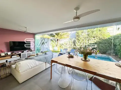 Sala integrada com sofá, TV e vista para varanda com piscina