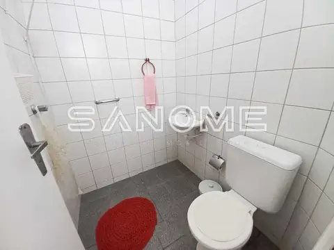 Banheiro com vaso sanitário e azulejos brancos